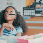 Shot of a young girl looking bored while playing at a school desk